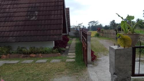 a fence next to a house with a yard at Nan Bungalows Tetebatu in Tetebatu