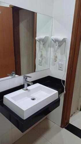 a bathroom with a white sink and a mirror at Casablanca Palace Hotel Frutal MG in Frutal