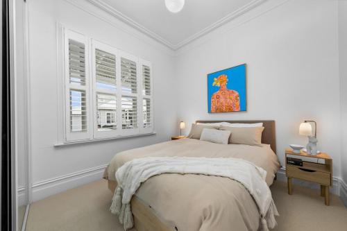 a white bedroom with a bed and two windows at Luxury boutique bay retreat in Williamstown