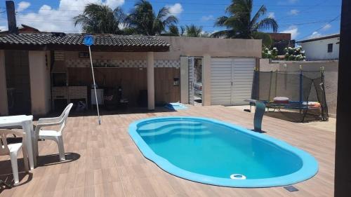 a large swimming pool on a patio with a table and a chair at Casa de Praia em Jaua in Camaçari