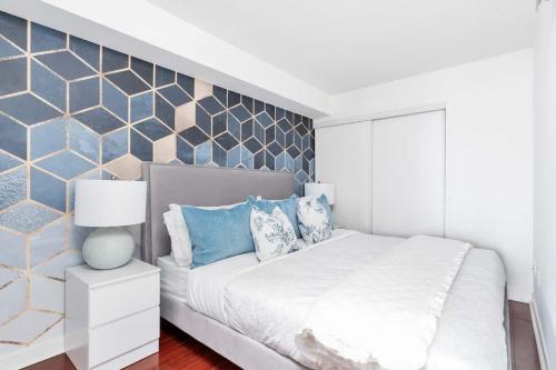 a bedroom with a white bed with blue pillows at Charming Condo w Private Patio in Quiet Capreol in Toronto