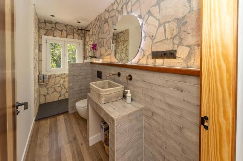 un bagno in pietra con lavandino e specchio di Cortijillo La Molinera a Jerez del Marquesado