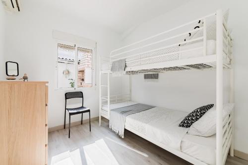 a bedroom with white bunk beds and a chair at Hogar con encanto a 10 min del centro de Valencia in Valencia