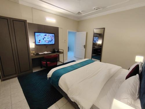 a bedroom with a bed and a desk and a television at مركز السراج للوحدات المخدومة in Jeddah