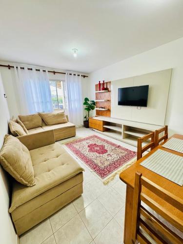a living room with a couch and a flat screen tv at Apartamento coração de arraial in Arraial do Cabo