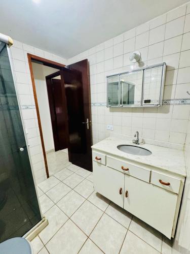 a bathroom with a sink and a mirror and a shower at Apartamento coração de arraial in Arraial do Cabo