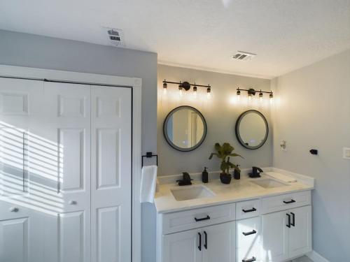 a white bathroom with two sinks and two mirrors at Buckle n Boots BNB - 20 minutes to downtown and pool in Houston