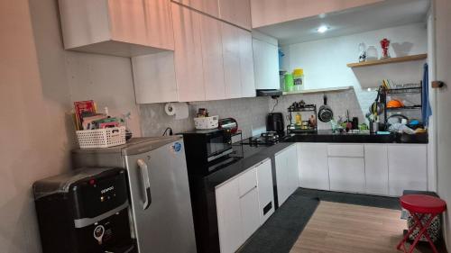 uma pequena cozinha com armários brancos e uma geladeira em Dago Family Stay em Bandung
