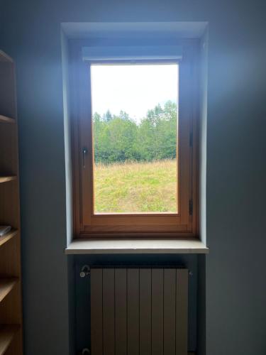 a window in a room with a field behind it at Relax, Comfort & Alps Adventures in Chiusa di Pesio