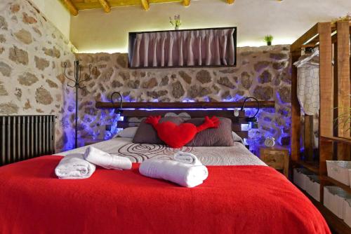 a bedroom with a red bed with towels on it at Casa Rural El Cuco in Robledillo
