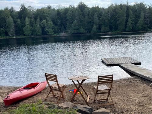 a table and two chairs and a boat next to a dock at Algonquin Waterfront and Winter Paradise With Sunsets in Algonquin Highlands