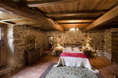 a bedroom with a large bed in a stone building at La Calleja in Arzúa
