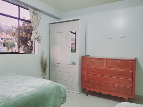 a bedroom with a bed and a dresser and a window at Acowasi in Acopampa