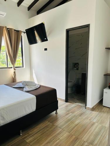 a bedroom with a bed and a sliding glass door at Hotel Paraiso Cañaveral in Santa Fe de Antioquia