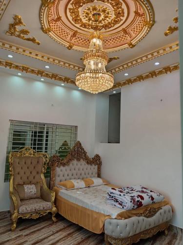 a bedroom with a bed and a chandelier and a chair at Rajmaya Tower in Sylhet