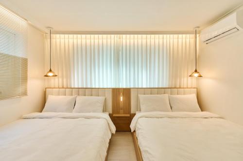 two beds in a room with a window at Ella Stay 서울 잠실 롯데월드 근처 천호동 강동경희대병원 5호선 올림픽공원역 KSPO #초역세권 #최고급 호텔침구 in Seoul