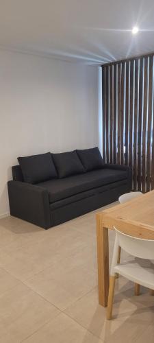 Una sala de estar con un sofá negro y una mesa. en Zafiro Apartments 4 pax, en Buenos Aires