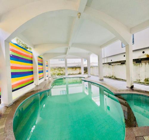 a swimming pool in a building with a colorful wall at Airport villa in Chewarra
