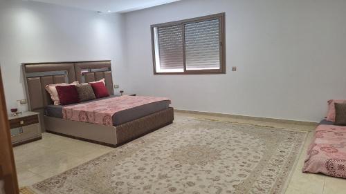 a bedroom with two beds and a window and a rug at Chambres au sein d'une villa in Rabat