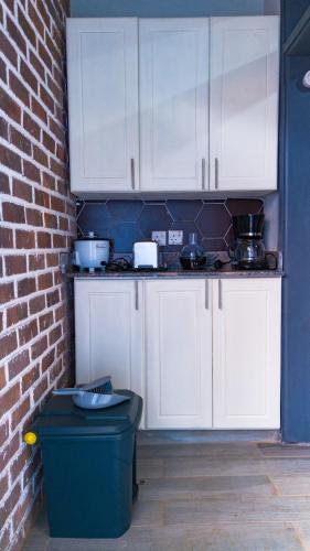 a kitchen with white cabinets and a brick wall at The apartments-Bwebajja in Bwebajja