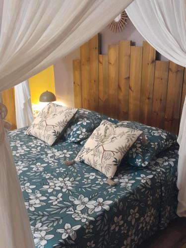a bed with a green comforter and pillows at Ti’Bou des Îles de Guadeloupe in Le Moule