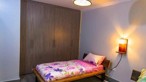 a bedroom with a bed and a lamp on a wall at The apartments-Bwebajja in Bwebajja