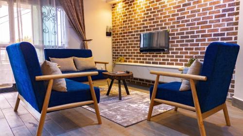 a living room with blue chairs and a brick wall at The apartments-Bwebajja in Bwebajja