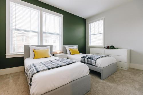 2 Betten in einem Zimmer mit grünen Wänden und Fenstern in der Unterkunft Birdsong Bungalow - Hot Tub, Game Room, Fire Pit in Charlotte