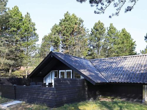 a house with a black roof with trees in the background at 4 person holiday home in Oksbøl-By Traum in Oksbøl