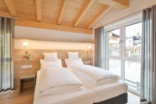 two beds in a room with a large window at Schlosskopf Suiten in Sankt Anton am Arlberg