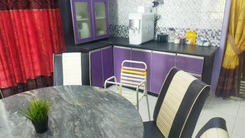 a kitchen with a table and chairs and purple cabinets at Homestay 43 Taman Sekaya in Guar Chempedak