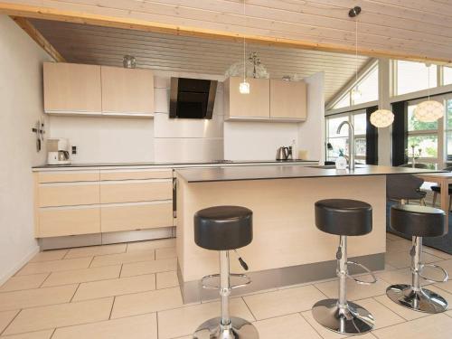 a kitchen with a counter and stools in it at Luxury Beach House with Spa - By Traum Ferienwohnungen in Sjølund
