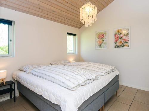 a bedroom with a large white bed with a chandelier at Luxury Beach House with Spa - By Traum Ferienwohnungen in Sjølund