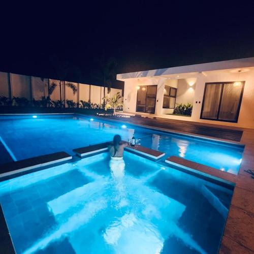 a person sitting in a swimming pool at night at Casa Fira - Beach House in San José de Guatemala