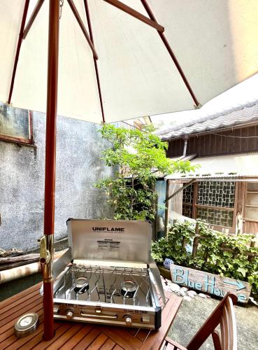 an outdoor grill on a deck with an umbrella at BLUE HOUSE - Traditional Home - 5min, Beach, Bus, Train in Beppu