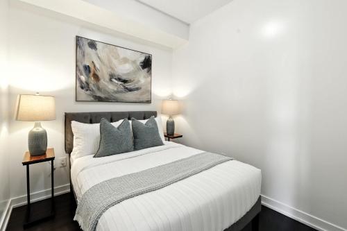 a white bedroom with a bed and two lamps at Modern Lakefront Escape Walk to Waterfront in Toronto