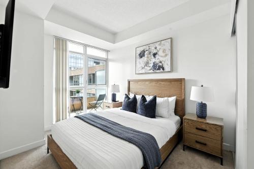 a white bedroom with a large bed and a window at Modern Lakefront Escape Walk to Waterfront in Toronto