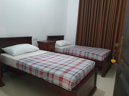 Dos camas en una habitación de hotel con faldas. en Joy living home, en Homagama