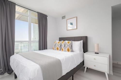 een witte slaapkamer met een bed en een raam bij Toronto Getaway 2BR Condo w City Views in Toronto