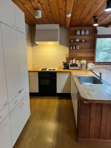 a kitchen with white cabinets and a sink at CabinC Private Fireplace, BBQ, Lake Saiko MtFuji in Narusawa