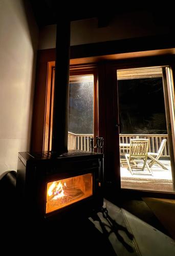 a fireplace in a room with a view of a porch at CabinC Private Fireplace, BBQ, Lake Saiko MtFuji in Narusawa