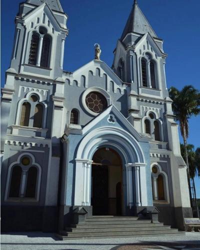 a white church with a steeple and a palm tree at Rancho Victória in Caconde