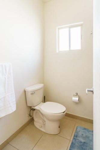a bathroom with a white toilet and a window at Santa Bárbara wifi Factura in Hermosillo