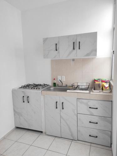 a white kitchen with a sink and a stove at Departamento Luz de Lino in Guadalajara