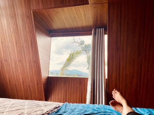 a person laying on a bed looking out a window at Biển Hồ Garden Glamping in Bien Ho