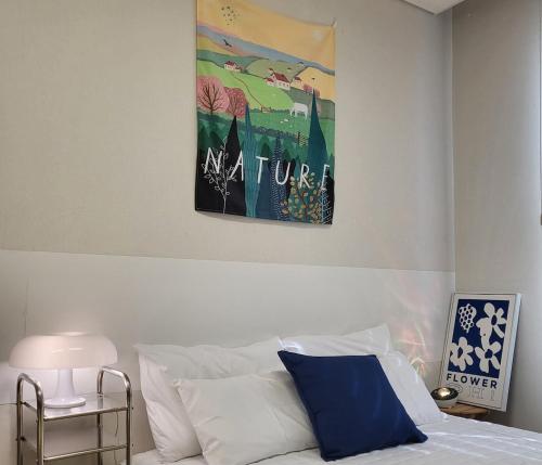 a painting above a bed in a bedroom at #Long-term accommodation inquiries#Suwon Convention Center#Gwanggyo Lake Park#Daily bedding change in Suwon