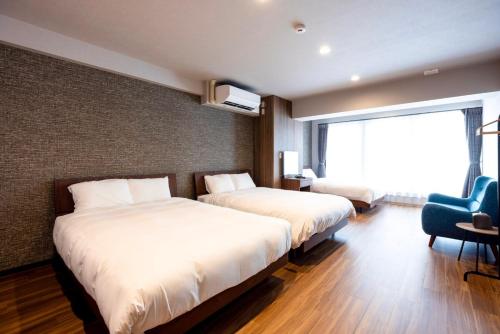 a hotel room with two beds and a chair at Amp Flat Arc Bliss 2A in Chikushino