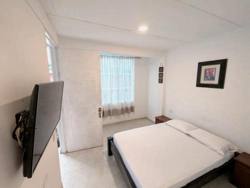 a white bedroom with a bed and a television at Casa corazón del pueblo in Calima