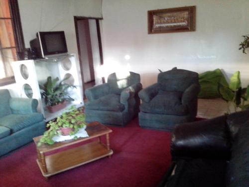a living room with three chairs and a table at Pensión Hospital in Maipo