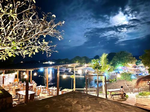 a restaurant with a view of a river at night at The Kudi in Nusa Lembongan